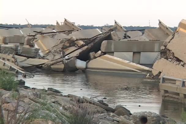 El agua fluye alrededor de una calzada destruida — Vídeo de stock