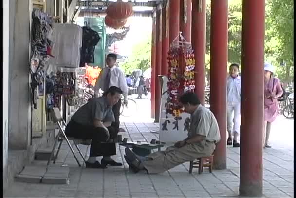 Men play a board game outside shop — Stock Video