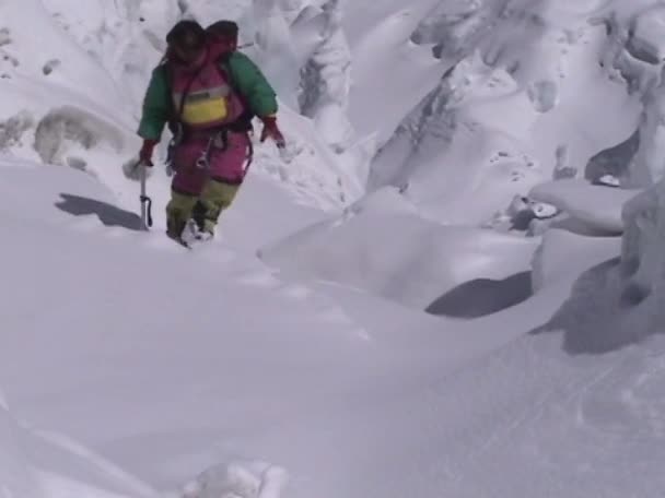 Альпинист взбирается на снежное поле — стоковое видео