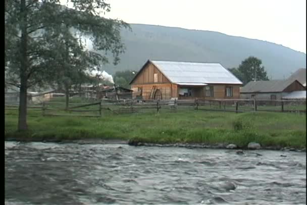 Fiume scorre di fronte ad un casale rurale — Video Stock