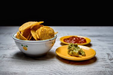 Guacamole soslu nachos ve biber soslu beyaz ahşap masa.