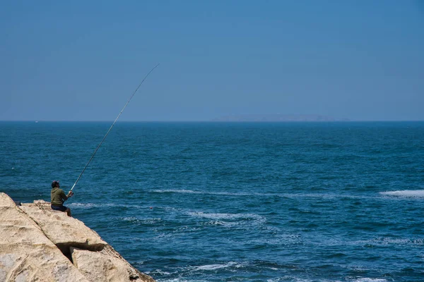 fisherman fishing in ocean from the rocks