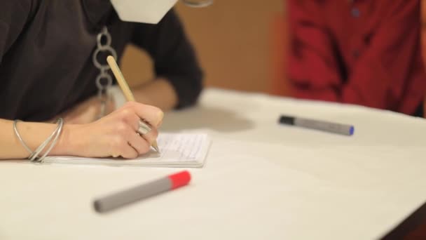 Chica escribe en el evento con un marcador de lápiz en una hoja — Vídeo de stock