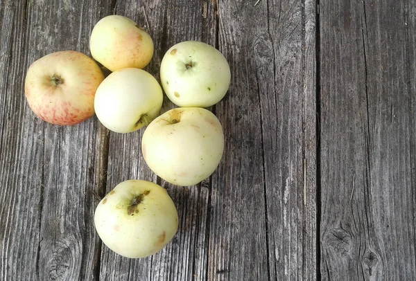 six ripe light green apples on old boards on a bright day in early autumn