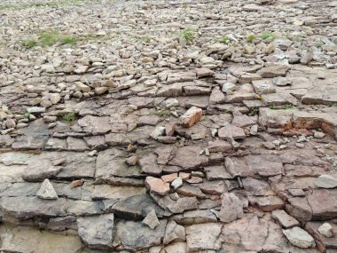   Gölün kıyısındaki kayalık kayalar ve taş parçaları, aralarında çimen kırıntıları bulunan gri renkli taşlar doğal bir arka plan olarak kullanılabilir.        