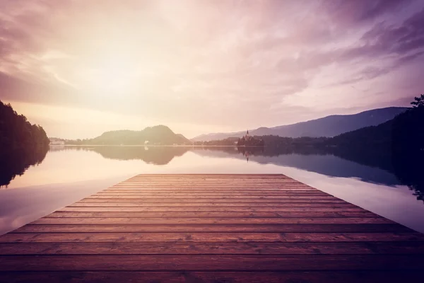 Фантастичний захід сонця в альпійському озері з дерев'яним пірсом — стокове фото