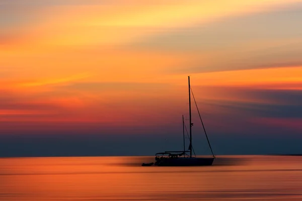 Захід сонця над морем з однією яхтою — стокове фото