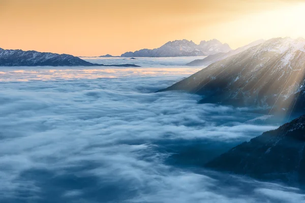 Pôr do sol dourado sobre nuvens e picos de montanha — Fotografia de Stock