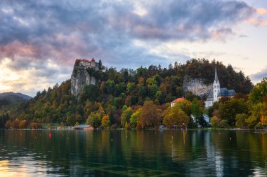 Slovenya 'daki Bled Gölü' nün (Blejsko jezero) günbatımında uçurumdaki Bled kalesinin manzarası, renkli gökyüzü ile muhteşem sonbahar manzarası. Dış seyahat arka planı