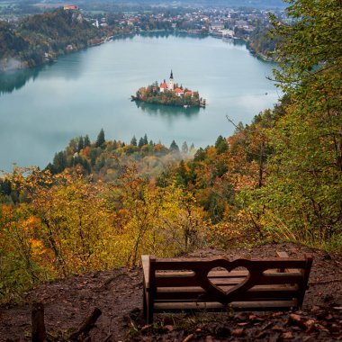 Ünlü alp gölü manzaralı ahşap bank (Blejsko jezero), kilisesi, dağları ve gökyüzü olan ada, muhteşem sonbahar manzarası, dış seyahat arka planı, Slovenya