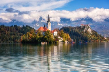 Slovenya 'daki ünlü Alp Bled Gölü (Blejsko jezero), muhteşem sonbahar manzarası. Göl manzaralı, kiliseli ada, Kanlı kale, dağlar ve bulutlu mavi gökyüzü, açık hava seyahati