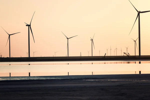 乌克兰赫尔松州 风电场和日落时咸咸的锡瓦什湖 黄褐色的风景 风力涡轮机 太阳光和水中的倒影映衬下的工业景观 — 图库照片