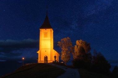 Slovenya 'nın başkenti tepedeki aydınlatılmış Jamnik Kilisesi St Primus ve Felician' ın manzarası. Mavi yıldızlı gökyüzü ile güzel bir manzara, dış seyahat arka planı, ünlü turistik eğlence.