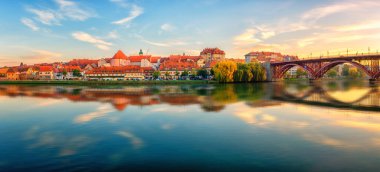 Slovenya 'nın başkenti Drava nehrindeki Maribor Eski Köprüsü' nün (Stari Most) muhteşem manzarası. Mavi gökyüzü ve yansıması olan manzaralı şehir manzarası, duvar kağıdı veya rehber kitap için seyahat arkaplanı