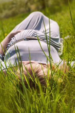 Baharda çiçek açan bahçede hamile bir kadın.