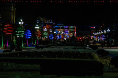 Gece şehir manzarası, yeni yıl çelenkleriyle süslenmiş. Farklı renkler yanıyor. Yeni yıl arifesi, Noel