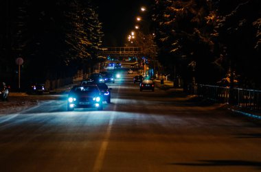 Arabalar kış gecesi şehrinden geçer. Fenerlerin ve farların ışığı.