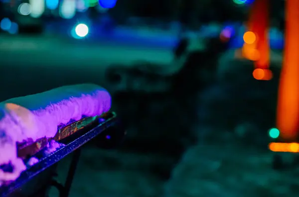 Dükkan kışın sokakta duruyor, karda, çok renkli tatil lambalarıyla aydınlatılıyor. Yeni yıl arifesi