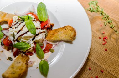 Keçi peynirli salata, domates, beyaz tabakta baget. Yakın plan.