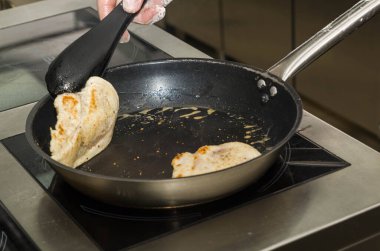 Aşçı tavada tavuk göğsü kızartıyor. Eller yukarı. Kızarmış duman. Yemek pişirme süreci