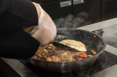 Aşçı tavada tavuk göğsü kızartıyor. Eller yukarı. Kızarmış duman. Yemek pişirme süreci