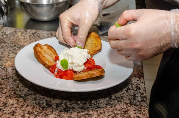 Tabağı yakın çekimde servis ediyorum. Şefin elleri beyaz tabakta domatesli, baget ve yumuşak peynirli