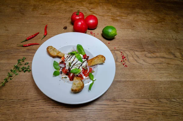 Keçi peynirli salata, domates, beyaz tabakta baget. Yakın plan.