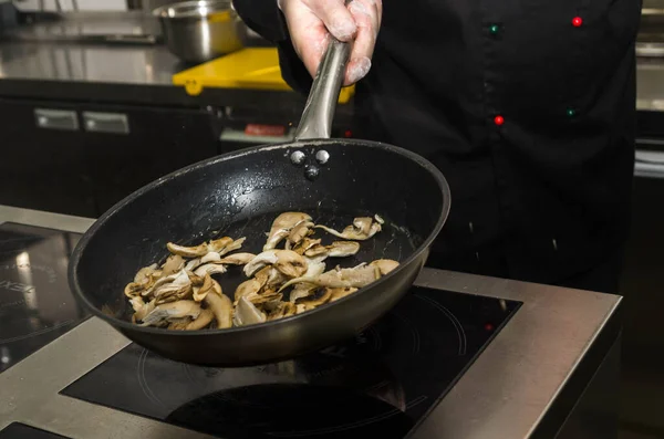 Aşçı tavada mantar kızartıyor, fırlatıyor ve ters çeviriyor. Yemek pişirme süreci