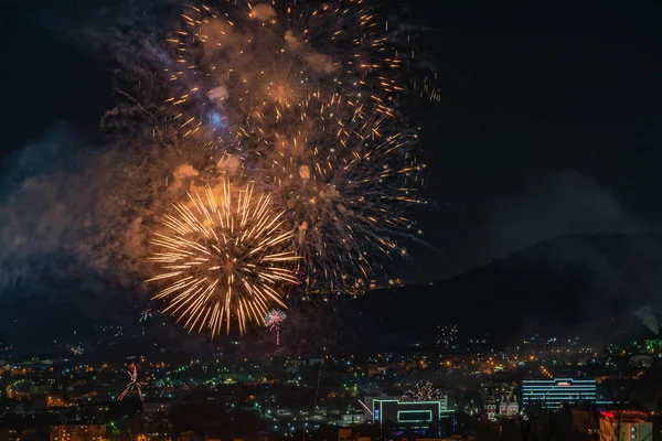 Havai fişekler göz kamaştırıcı bir manzarayla gökyüzünü aydınlatır. Bokeh arka planıyla şehrin üzerinde renkli havai fişekler. Soyut festival arkaplanı