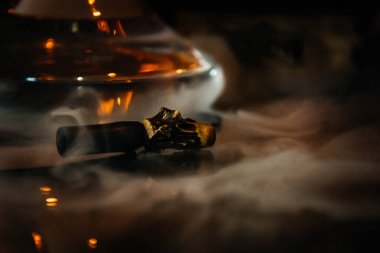 Duman bulutunda nargile ağızlığı. Arka planda nargile şişesi var. Koyu arkaplan