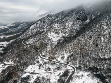 Kar altındaki dağ zirvesi alçak bulutların arka planına karşı. Pyatigorsk Dağı, Beshtau Dağı.