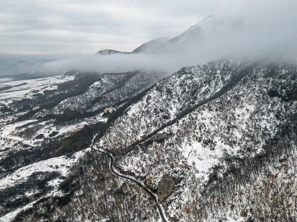 Kar altındaki dağ zirvesi alçak bulutların arka planına karşı. Pyatigorsk Dağı, Beshtau Dağı.