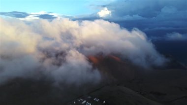 Bulutların üstündeki drone görüntüleri. Gün batımında, dağlık arazide kocaman kabarık bulutlar..