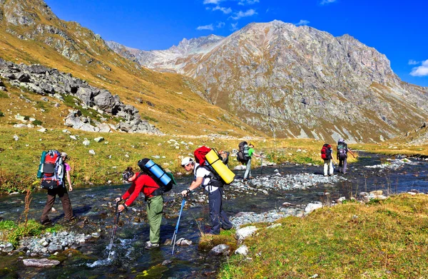 I turisti superano un fiume di montagna — Foto Stock