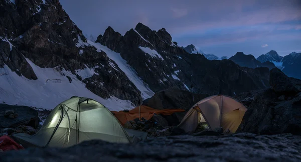 Mountaineers camps in very high craggy mountains beside glacier. — Stock Photo, Image