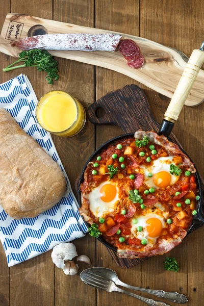 Bakade ägg med chorizo, potatis och tomater i en skål på bordet. ovanifrån — Stockfoto