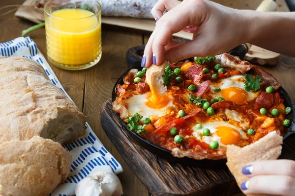 Kézi dip kenyér flamenco tojásokat vagy huevos la flamenca, andalúz ételeket — Stock Fotó