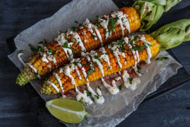 Elote veya Meksika ızgara mısır cotija peynir ve biber tozu ile servis.