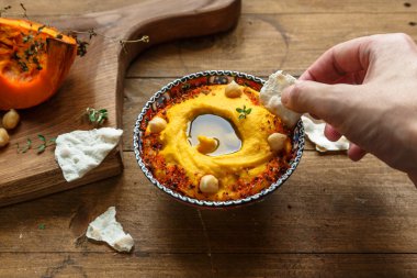 Adam dip ekmek içine koyu ahşap arka plan üzerinde kabak humus. Tonlama. seçici odak