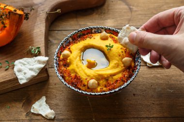 Adam dip ekmek içine koyu ahşap arka plan üzerinde kabak humus. Tonlama. seçici odak
