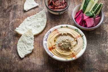 Koyu ahşap arka planda taze sebzeli balkabağı humusu.