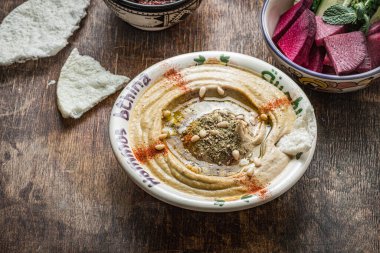 Koyu ahşap arka planda taze sebzeli balkabağı humusu.