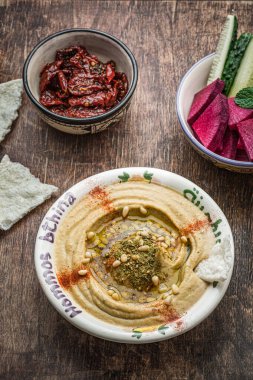 Koyu ahşap arka planda taze sebzeli balkabağı humusu.