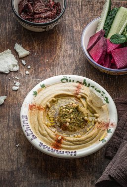 Koyu ahşap arka planda taze sebzeli balkabağı humusu.