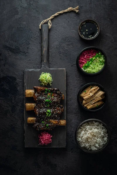 Estofado de carne de res costillas cortas, estilo asiático con arroz y rábano, foto oscura, acostado plano — Foto de Stock
