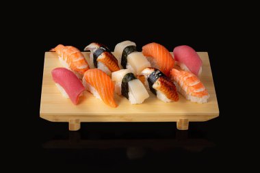 Suşi seti. Somon balıklı rulo kırmızı havyar ve siyah arka planda sebze.