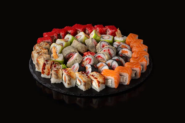 Set de sushi. Rollos con caviar rojo anguila salmón y verduras sobre fondo negro — Foto de Stock