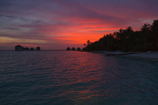 Закат на Мальдивах с видом на лагуну и бунгало
