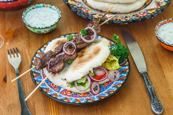 Греческий сувлаки подается традиционным способом, на пита хлеб с луком кольца и лимон — стоковое фото