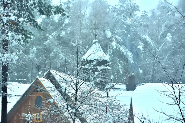 Ormanda, kışın karla kaplı ahşap bir kilise. 